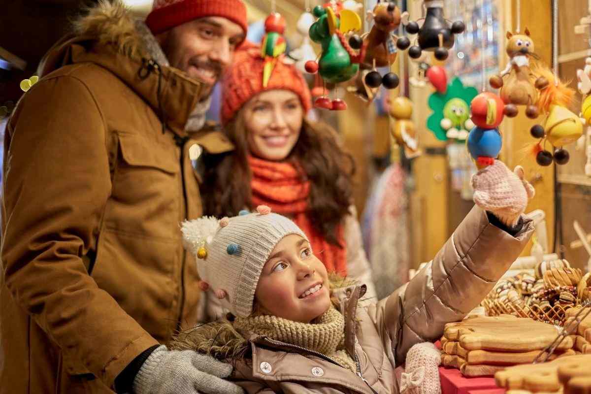 Famiglia felice e sorridente osserva il mercatino natalizio
