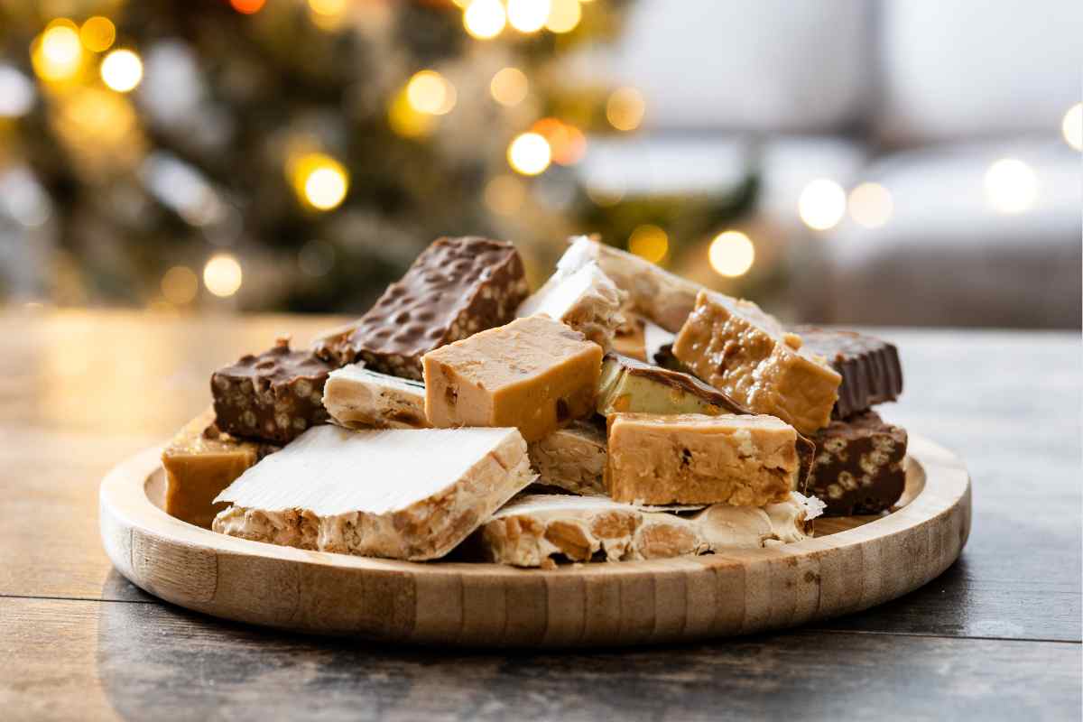 Torroncini su un piatto davanti a un albero di natale