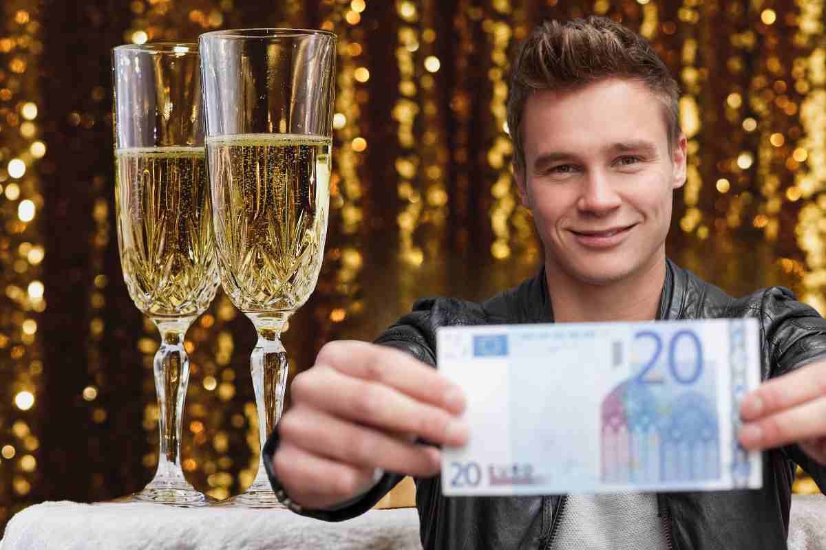 ragazzo mostra 20 euro e alle spalle due flute pieni di prosecco per il capodanno