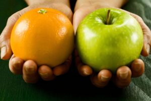Mela e arancia tenute in mano