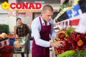 cliente e commesso in un supermercato e la dicitura conad supermercati aperti