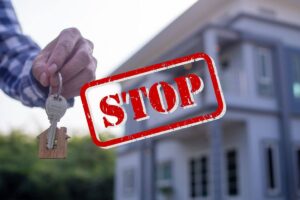 casa in vendita con uomo con le chiavi in mano e scritta stop in evidenza